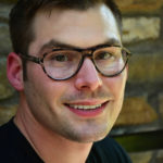 A man with glasses smiling for the camera.